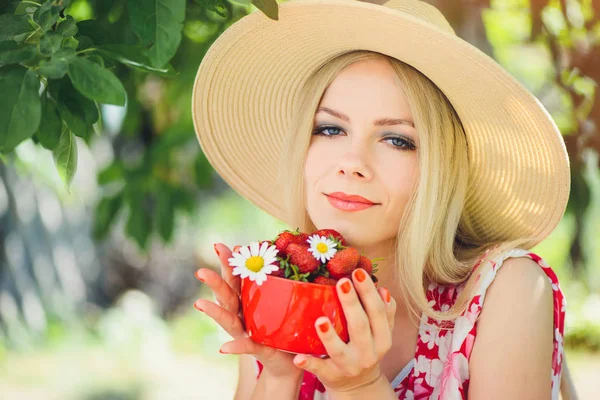 年轻温柔的金发女人与草莓在一个碗里 在一个绿色的花园一个夏日阳光明媚的一天 温暖的夏天色调的形象 自我照顾和健康的生活方式 — 图库照片