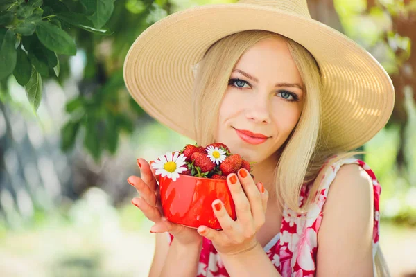 年轻温柔的金发女人与草莓在一个碗里 在一个绿色的花园一个夏日阳光明媚的一天 温暖的夏天色调的形象 自我照顾和健康的生活方式 — 图库照片