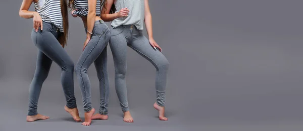 three women in good form of pop in the legends of Push-Up on a gray background, fashionable advertising advertising space for text, increased priests,