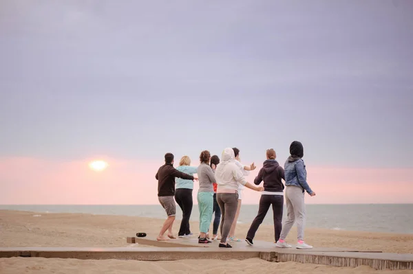 group of people doing exercises at sunrise meet the sun, doing yoga, a healthy lifestyle.