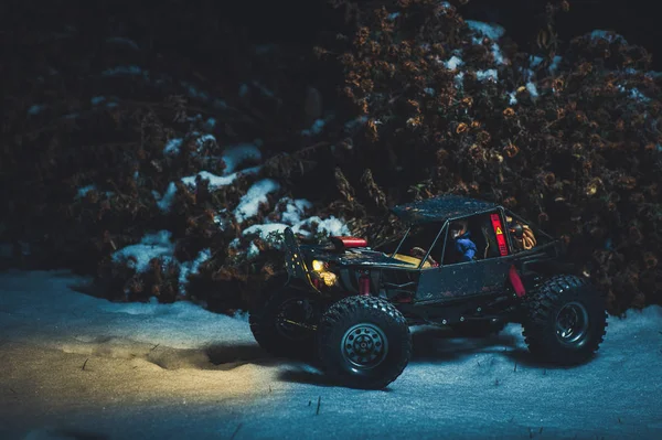 Voiture radiocommandée dans la neige la nuit, les lumières brillent. Cadeau de Noël rc voiture — Photo