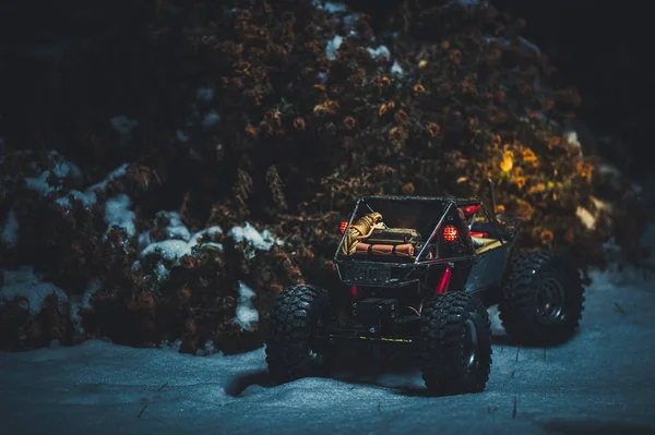 Радиоуправляемая машина в снегу ночью, свет светит. Рождественский подарок RC автомобиль задний вид — стоковое фото