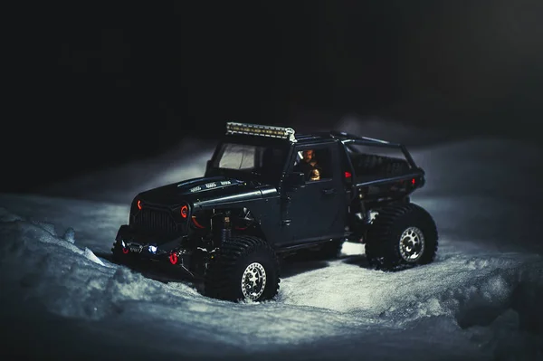 Radio-controlled car in the snow at night, lights shine. Christmas entertainment gift rc car.