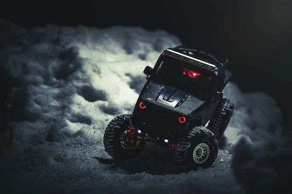 Radio-controlled car in the snow at night, lights shine. Christmas entertainment gift rc car.