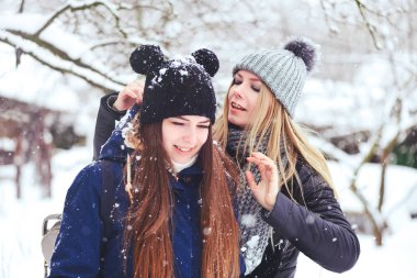 komik ve mutlu iki güzel kız arkadaşım karda kışın çok kar ve kış giysi oynamak. sarışın ve esmer bakım ve duygular.