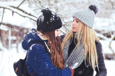 komik ve mutlu iki güzel kız arkadaşım karda kışın çok kar ve kış giysi oynamak. sarışın ve esmer bakım ve duygular.