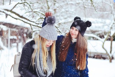 komik ve mutlu iki güzel kız arkadaşım karda kışın çok kar ve kış giysi oynamak. sarışın ve esmer bakım ve duygular.
