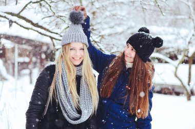 komik ve mutlu iki güzel kız arkadaşım karda kışın çok kar ve kış giysi oynamak. sarışın ve esmer bakım ve duygular.
