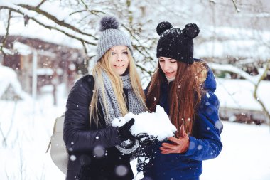 komik ve mutlu iki güzel kız arkadaşım karda kışın çok kar ve kış giysi oynamak. yeme kar neşeli yaramaz reklam.