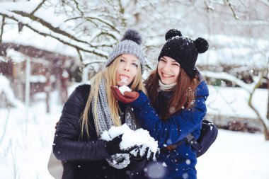komik ve mutlu iki güzel kız arkadaşım karda kışın çok kar ve kış giysi oynamak. yeme kar neşeli yaramaz reklam.
