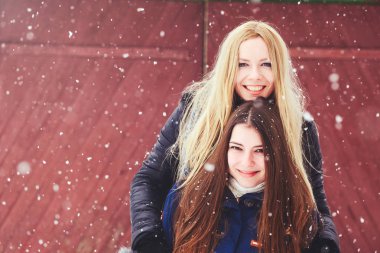 komik ve mutlu iki güzel kız arkadaşım karda kışın çok kar ve kış giysi oynamak. sarışın ve esmer bakım ve duygular.