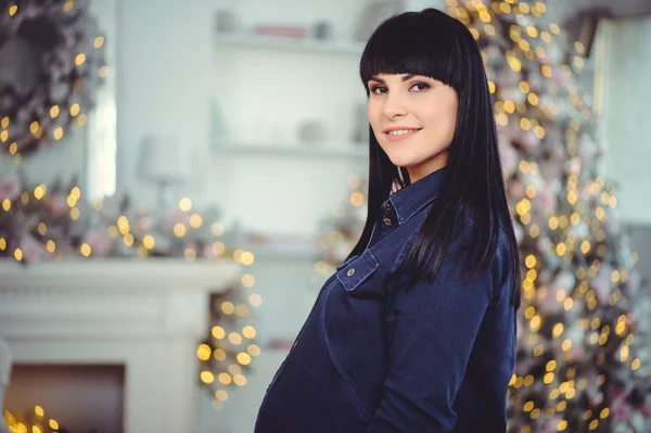 人和期望的概念 快乐的孕妇 站在一个房间里 背景是穿着牛仔裤衣服的圣诞树 — 图库照片