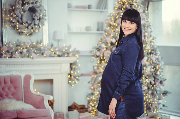 Kavramı gebelik, aşk, insanlar ve beklentileri - mutlu hamile kadın, kot pantolon Noel ağacı arka planı bir odada giyim - resim standları