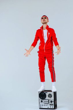 retro bir ses kayıt cihazı ile oturan kırmızı spor takım elbise giyen neşeli moda adam. 90 's gurur ve başarılı tarzı.