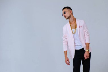 şık dostum sofistike pembe bir ceket ve siyah pantolon giyer altın bir zincir, duyguların ifade elleriyle jestleri.