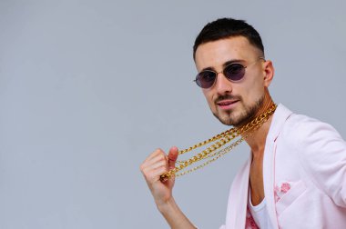 şık dostum sofistike pembe bir ceket ve siyah pantolon giyer altın bir zincir, duyguların ifade elleriyle jestleri.