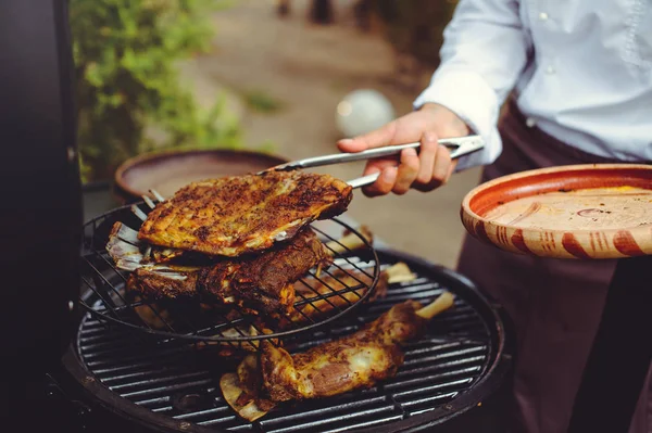 De chef-kok controleert het vlees op de grill. Gegrilde gouden ribben steaks, heerlijk eten — Stockfoto