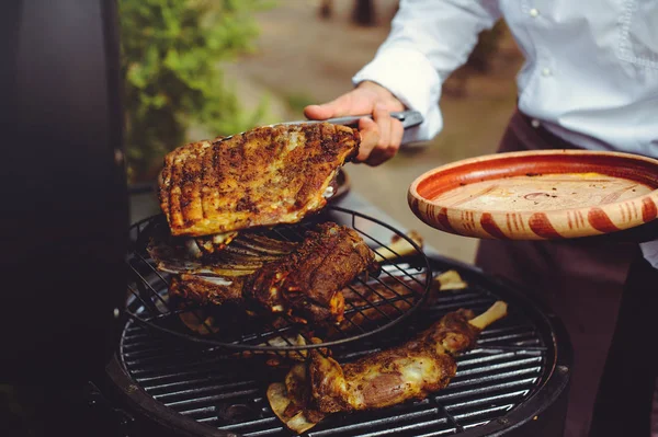 De chef-kok controleert het vlees op de grill. Gegrilde gouden ribben steaks, heerlijk eten — Stockfoto