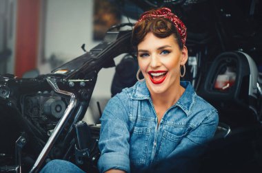 Güzel bir kız atölyede motosiklet tamir ediyor, poster stili, servis ve satış..