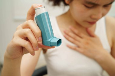 Astım ve kronik obstrüktif akciğer hastalığı KOAH, Asyalı genç ölçülü doz solunum cihazı kullanıyor..