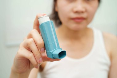 Astım ve kronik obstrüktif akciğer hastalığı KOAH, Asyalı genç ölçülü doz solunum cihazı kullanıyor..