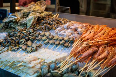 Asya gece pazarında sokak gıda standında karides, istiridye, deniz tarağı, kabuklu deniz ürünleri ve taze deniz ürünleri