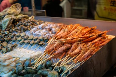 Asya gece pazarında sokak gıda standında karides, istiridye, deniz tarağı, kabuklu deniz ürünleri ve taze deniz ürünleri