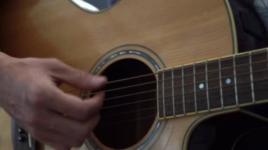 Gitarist akustik gitar oynarken stüdyo seçici odak yakın yukarı klavye ve el rock pop akorları oynuyor