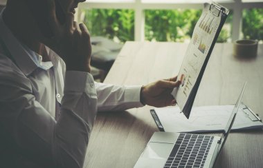 İş adamı pazarlama raporunu ve telefon ortağını kontrol ediyor.