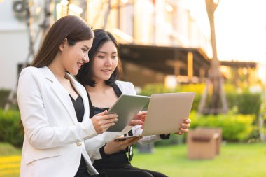 İki iş kadını açık hava parkında birlikte çalışıyor.