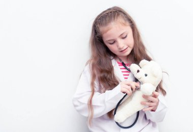 Küçük çocuk oyuncak ayı sağlık kontrolü için doktor takım elbise ve donanımları kullanıyor