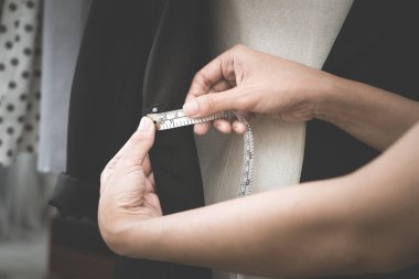 Moda tasarımcısı eli, ölçü bandıyla ceketi ölçüyor.