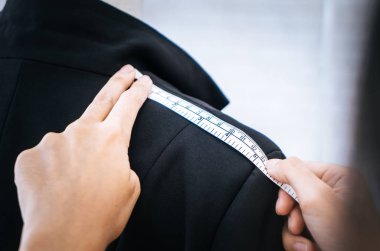 Moda Tasarımcısı el, ölçü bandıyla omuz ölçüyor.