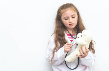 Küçük çocuk oyuncak ayı sağlık kontrolü için doktor takım elbise ve donanımları kullanıyor
