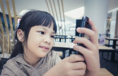 Asyalı çocuk kafede hoparlör telefonda konuşuyor