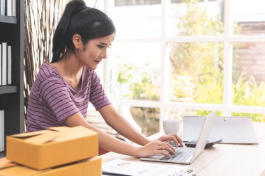 Evde çalışan mutlu Asyalı kadın dizüstü bilgisayar kullanıyor.