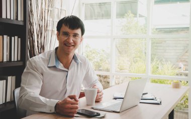 İşadamı ofiste kahve ve laptop içiyor.