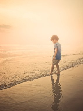 Altın sahilde okyanus dalgası ile oynayan çocuk