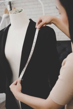 Kadın terzi, mezura ile ceketini ölçüyor.