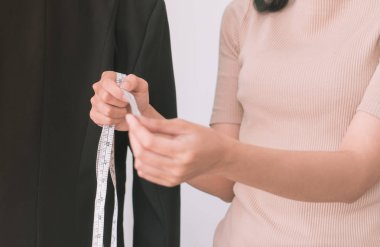 Kadın terzi, mezura ile ceketini ölçüyor.