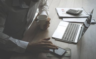 İş adamı finansal muhasebe nesneleri ile masada bilgisayar ve mobil kullanıyor