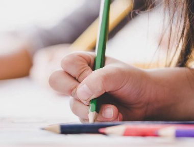 Çocuk el bir kağıt üzerinde yazma pratik renkli kalem kullanıyor.