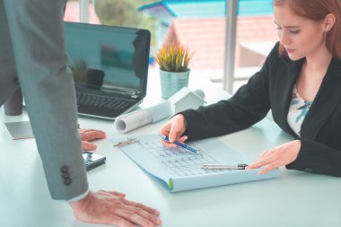 Bayan mimar patronuna emlak inşaatı planını gösteriyor. Mühendis de müşteriye inşaat planı öneriyor.