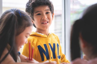 Yaratıcılık konsepti için sanat sınıfında Asyalı çocuklar oyuncak bebek boyuyor.