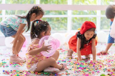 Çocuklar çocuk partisinde kağıt ve balon fırlatıyor.