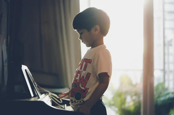 小さな男の子は自宅でピアノと音楽のタブレットで遊んでいます — ストック写真