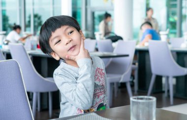 Asyalı çocuk kahvaltını kafede yapıyor.