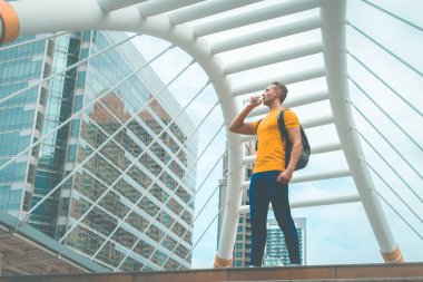 Sarı sportif adam sıcak gün açık su içiyor