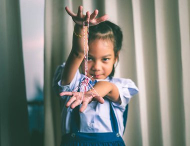 Asyalı kız şekil yapmak için rop iplik ile oynuyor