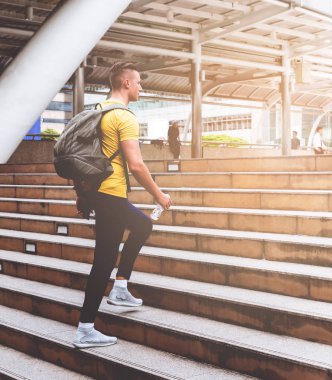 Erkek spor adamı modern şehirde merdivenden yürüyor